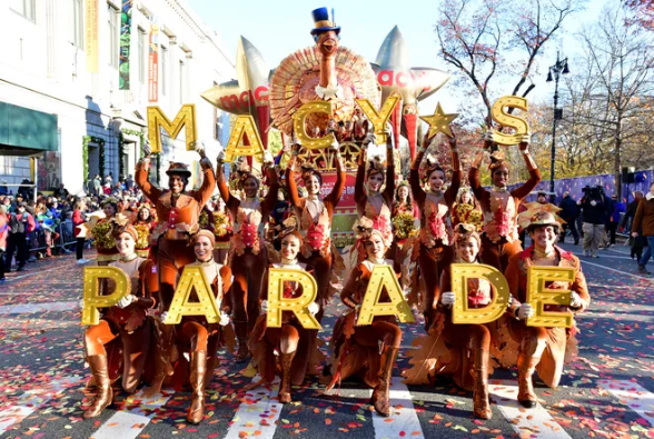 Cheerleaders holding up the sign saying Macy's Parade